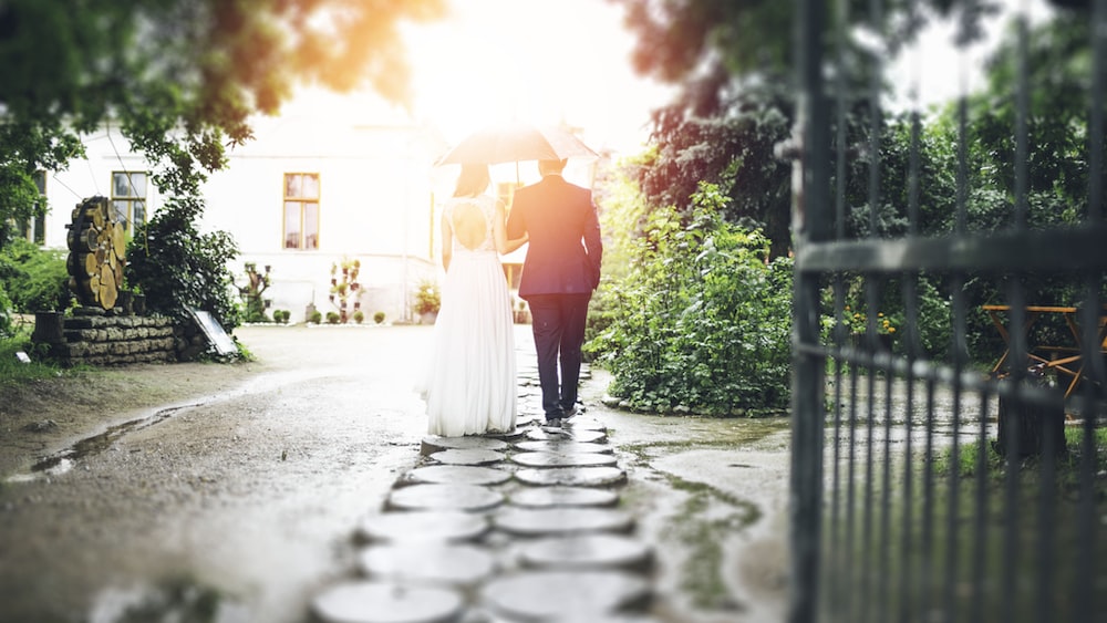 Blindfolded newlyweds walking down a stone walkway