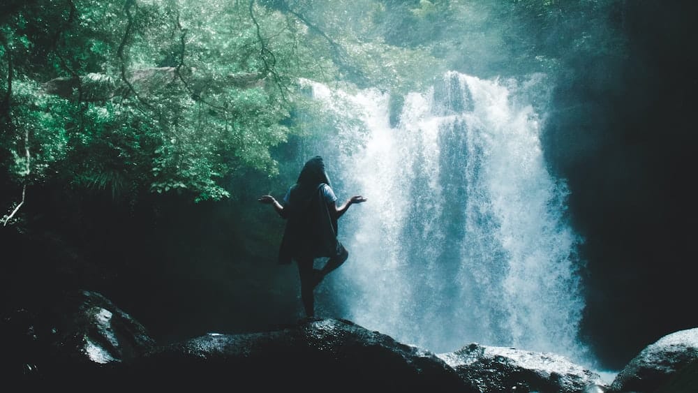 Connecting with Nature: Woman Practicing Yoga by Waterfall