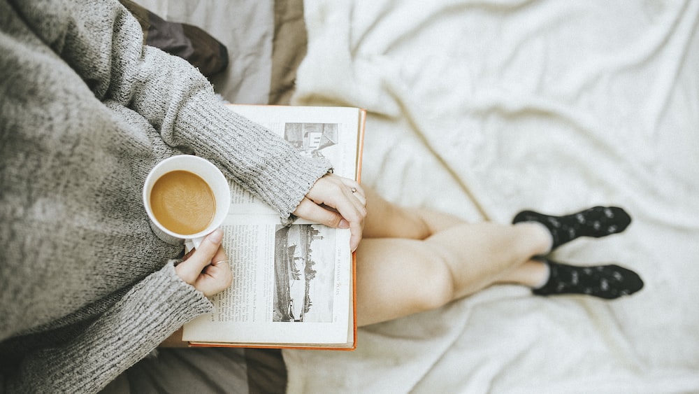 Embracing Self Improvement: A Woman Finding Inspiration in Reading and Coffee