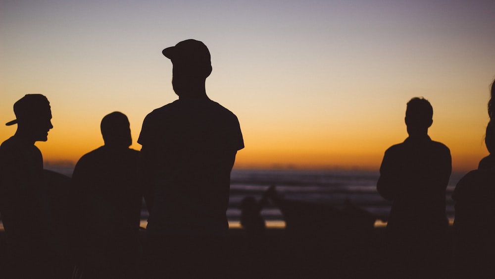 Group Mindfulness Activities: Silhouette of People Practicing Mindfulness at Piha Beach.