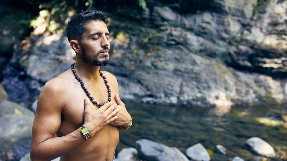 Man meditating near water: A mindfulness routine.