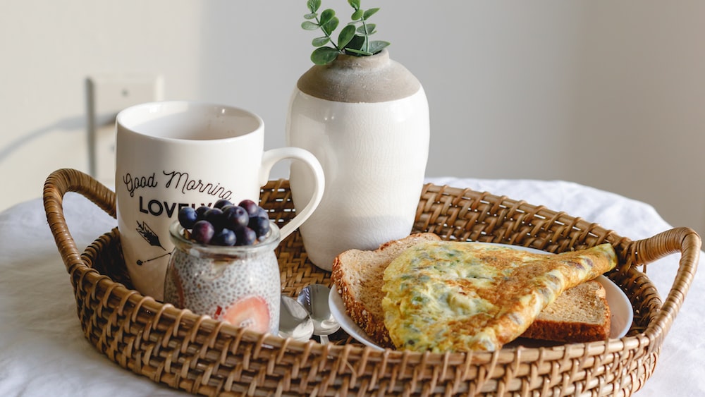 Mindful Breakfast: Omelet, Chia Pudding, and White Ceramic Mug on Brown Woven Tray