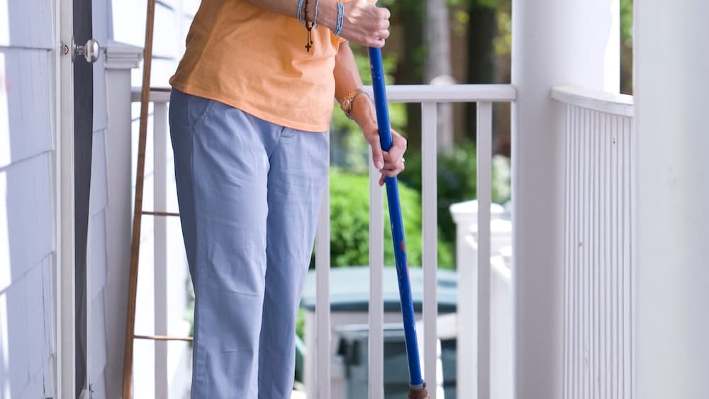 Mindful Cleaning: Woman Sweeping Porch to Reduce Indoor Contaminants