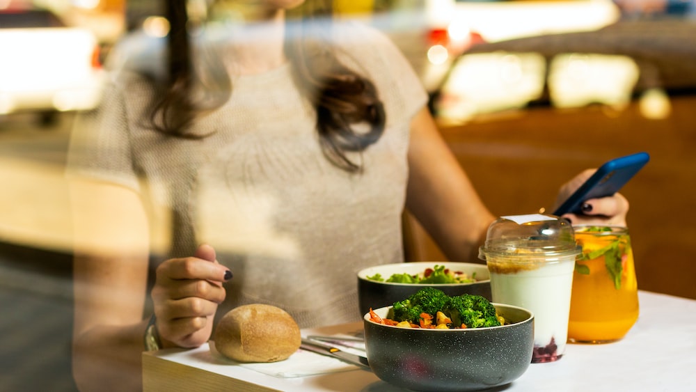Mindful Eating: Woman Enjoying Tasty Salad While Using Her Phone
