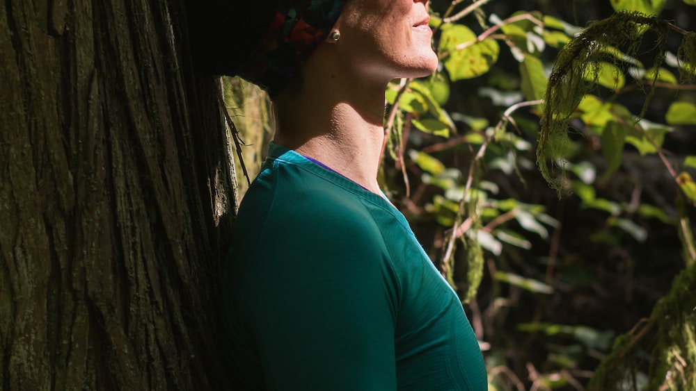 Mindful Forest Moment: Woman Standing by Tree in Green Shirt