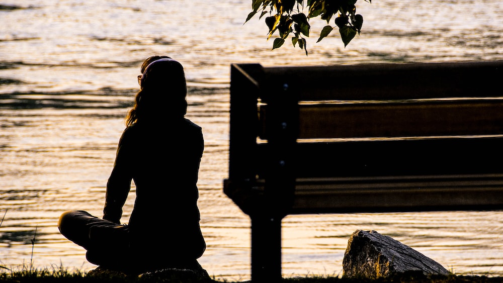 Mindful Reflection: Woman Meditating by the River at Sunset