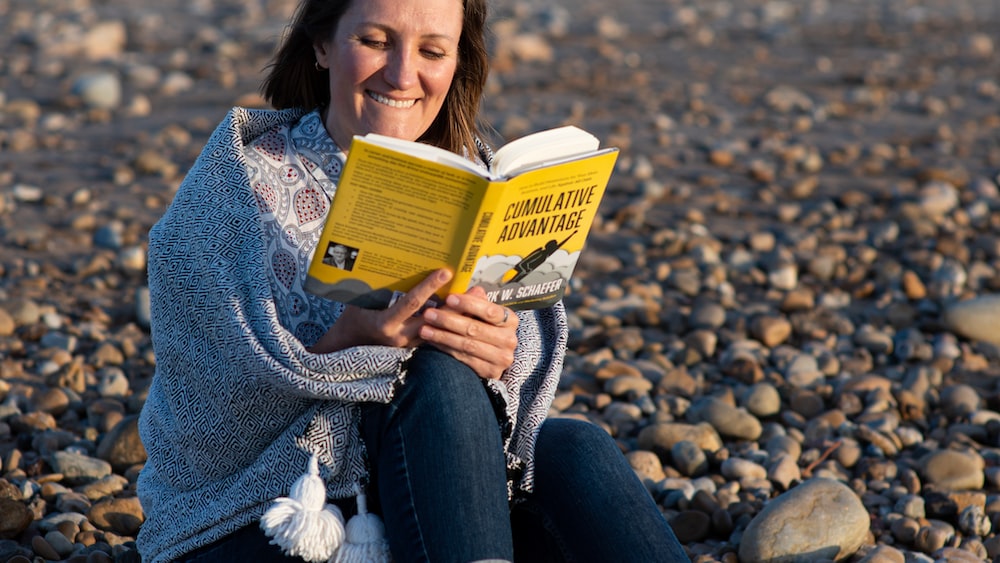 Relaxation and Personal Growth: Woman Reading on Beach at Sunset