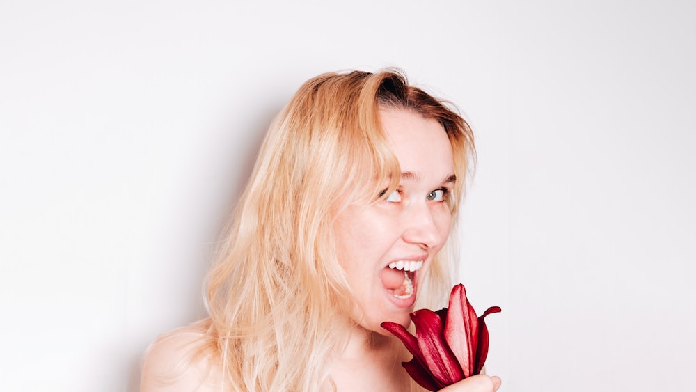 Self Improvement and Self Growth: Trustworthy Blonde Woman Holding a Red Tulip