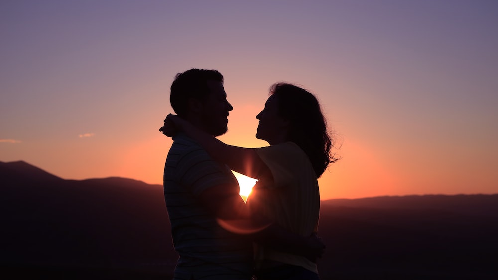 Silhouette of a couple hugging in the mountains.