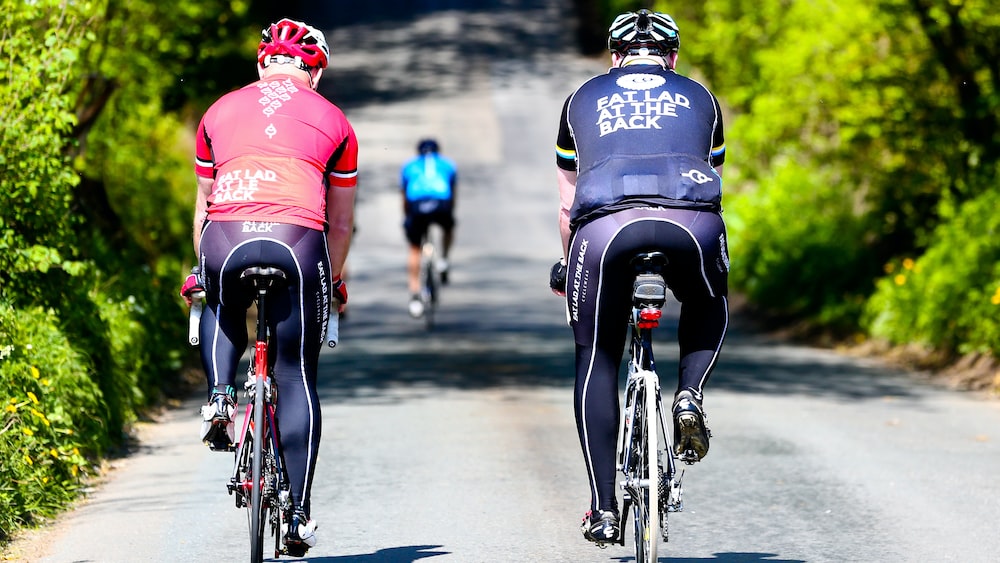 Two cyclists riding together on a sunny country lane.