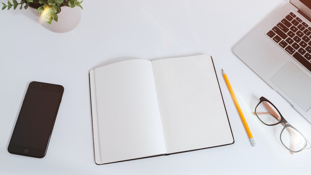 White work table with notes, smartphone and laptop - Illustrating Strong Work Ethic