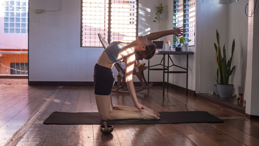 Woman practicing mindful yoga in black shorts and white tank top.
