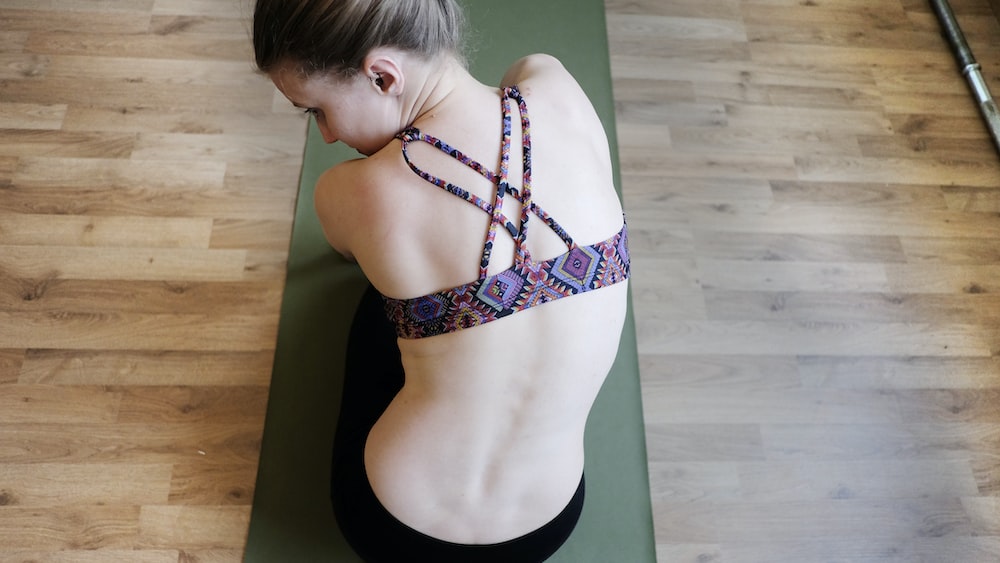 Yoga for Spine Health: Woman in Purple Sports Bra Demonstrates Mindful Stretching